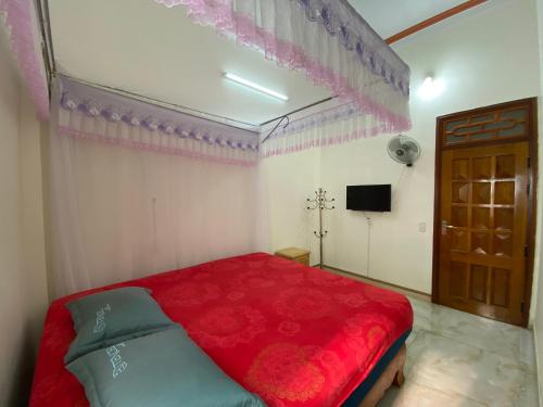 a bedroom with a red bed and a television at Tom Homestay in Yên Minh