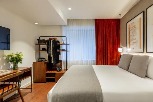 a bedroom with a bed and a desk and a red curtain at Hotel Indigo London - 1 Leicester Square by IHG in London