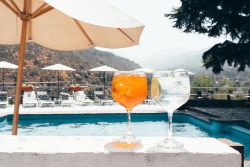 two wine glasses sitting on a ledge next to a pool at Casa Arrayán in Santiago