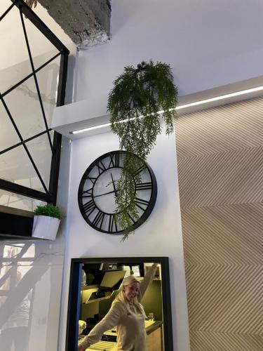 a woman standing in a room with a clock on the wall at Apartman Plaža Lux in Veliko Gradište