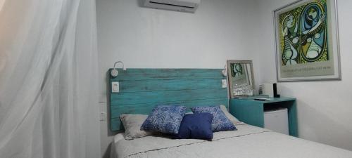 um quarto com uma cama e uma cabeceira de cama em madeira azul em Studio e Suite no Centro de Juquehy a 150mts da praia - Varanda e Serviço de Praia --- E MAIS Ofurô - Cozinha e Estacionamento nas unidades "STUDIO" -- TUDO NOVO em Juqueí