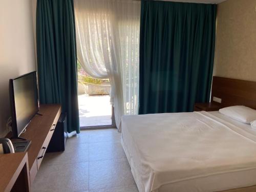 a bedroom with a bed and a television and a window at On Oda Oludeniz in Oludeniz