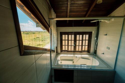 ein Bad mit einer Badewanne und einem Fenster in der Unterkunft Pousada Casa Aratuca - 200mt da praia in São Francisco do Sul