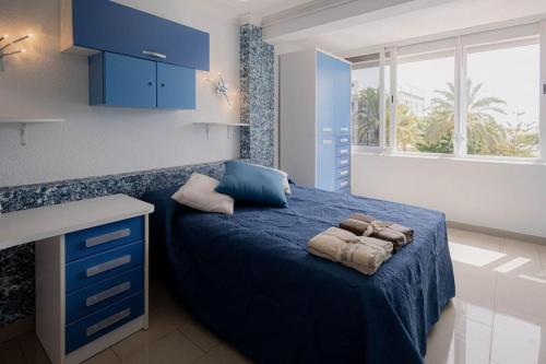 Un dormitorio con una cama azul con toallas. en Adosado en Costa Adeje, en Playa de las Américas