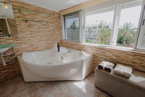 baño con una gran bañera blanca y una ventana en Adosado en Costa Adeje, en Playa de las Américas