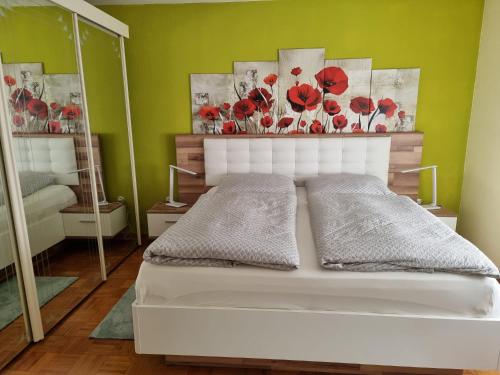 1 dormitorio con 1 cama blanca con flores rojas en la pared en Ferienwohnung Mohnblume 