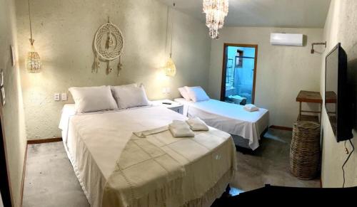 a bedroom with two beds and a mirror at Pousada Ybitu in São Miguel do Gostoso