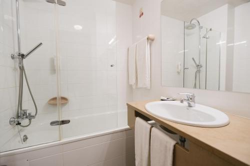 y baño blanco con lavabo y ducha. en Hotel Rainha D. Amélia, Arts & Leisure en Castelo Branco