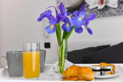 un jarrón con flores púrpuras y una taza de zumo de naranja en B&B La casa di Graz, en Reggio Emilia