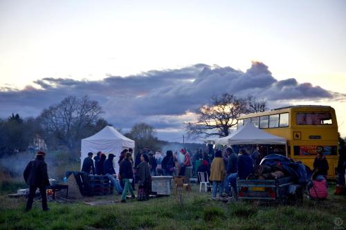 un grupo de personas de pie en un campo cerca de un autobús en Le YESLOWBUS en fête en Carla-Bayle