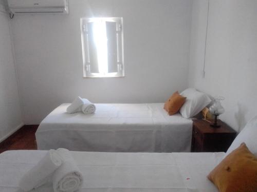 um quarto branco com 2 camas e uma janela em Casas da Saibreira - nº2 em Elvas