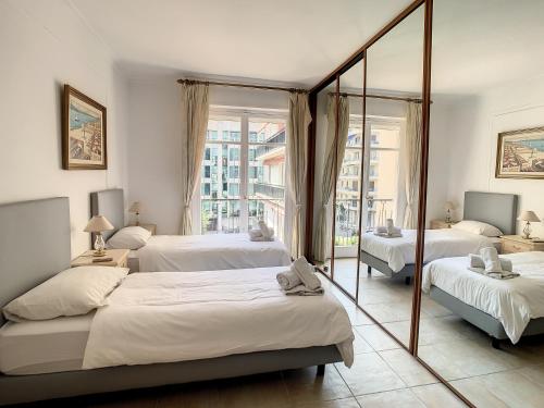- une chambre avec 3 lits et un miroir dans l'établissement Appartements Cannes Centre : Rond Point Duboys d'Angers, à Cannes