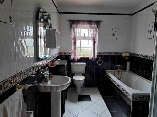a bathroom with a tub and a toilet and a sink at Spacious 6 Bed House 10 minutes from Knock Airport in Ballaghaderreen