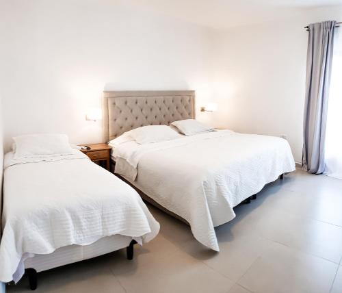 two beds in a bedroom with white sheets and pillows at SOMMER Y SOL in Cafayate