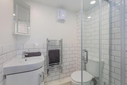 a white bathroom with a toilet and a sink at Central Windsor Modern Garden Flat, Walk 2 Sights in Windsor