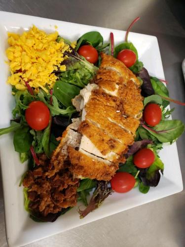 a plate of food with fish and a salad at White Sands Inn, Marina, Bar & Grill in Port Isabel