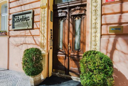 une porte en bois d'un bâtiment avec deux buissons dans l'établissement Sibelius Apartments, à Prague