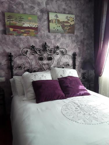 a bedroom with a large white bed with purple pillows at Casa Rural Mariluz in Santillana del Mar