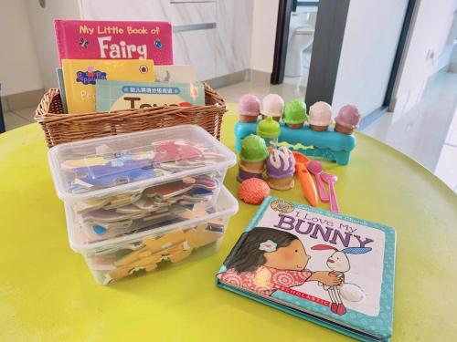 a table with a book and a basket and some toys at RelaxFamily 2-10Pax Trefoil Setia City Shah Alam SiS Homestay in Shah Alam
