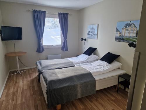 1 dormitorio con 1 cama con cortinas azules y ventana en Badeland Gjestegård, en Raufoss