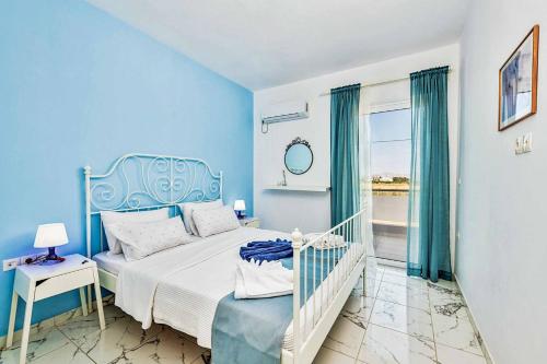 a blue bedroom with a bed and a window at Villa Xenos Tria in Tigaki