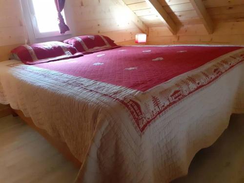 une chambre avec un grand lit avec une couverture rouge et blanche dans l'établissement Le loft des Pins, Chartreuse, à Entremont-le-Vieux