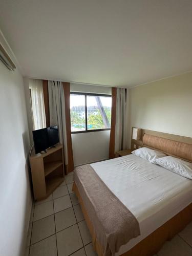 a bedroom with a bed and a flat screen tv at Beach class muro alto in Porto De Galinhas