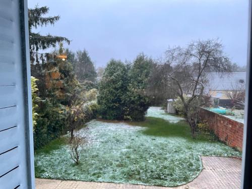 Elle offre une vue sur un jardin avec de la neige sur l'herbe. dans l'établissement Charmant T2 proche Disney, à Mortcerf
