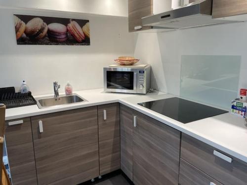 une cuisine avec un évier et un micro-ondes dans l'établissement Charmant T2 proche Disney, à Mortcerf