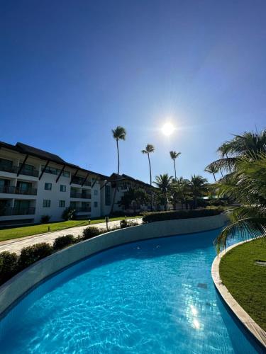 a large blue swimming pool with palm trees and condos at Beach class muro alto in Porto De Galinhas