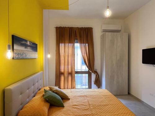 una camera da letto con un letto con pareti gialle e una finestra di B&B Salentocolors a Novoli