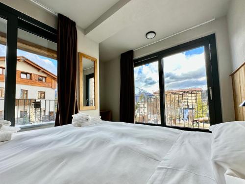 a bedroom with a large bed with a large window at Apartments Du Parc in Sauze dʼOulx