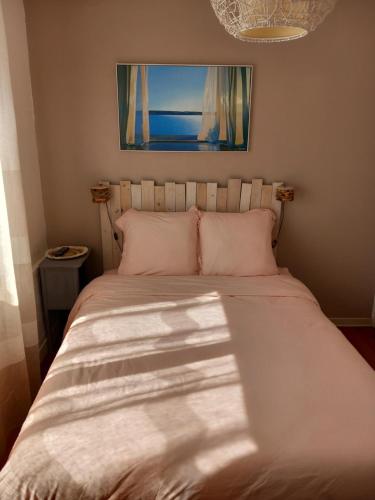 - un lit avec des draps blancs et une photo au-dessus dans l'établissement Les chambres aux portes de l'Authie, à Fort-Mahon-Plage