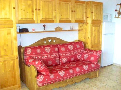 un canapé rouge dans une cuisine avec des armoires en bois dans l'établissement Appartement confortable à Hauteluce, 33 m² avec vue, à Hauteluce