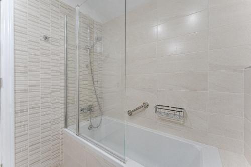 a white bathroom with a shower and a tub at Ferienwohnung Tower Penthouse Parque Santiago I in Playa de las Americas