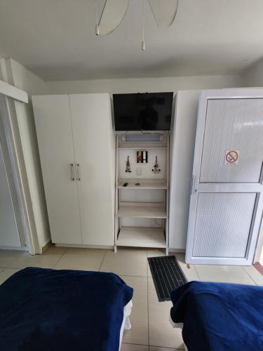 a bedroom with white cabinets and a flat screen tv at Driftsands Sea View Flats in Uvongo Beach