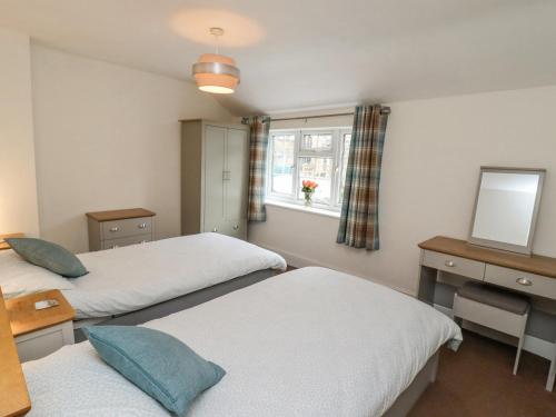 two beds in a room with a window and a mirror at Riverbank View in Whitby