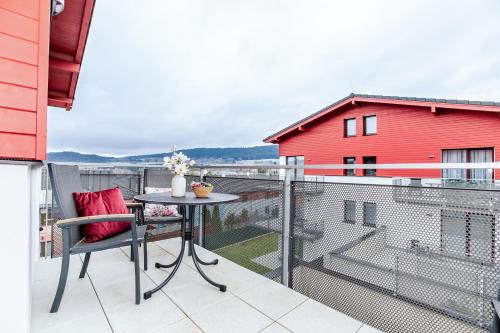 a balcony with a table and a red building at KORZO Lipno in Lipno nad Vltavou