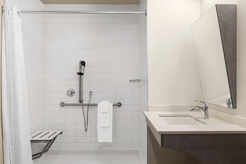 a white bathroom with a shower and a sink at Microtel Inn & Suites by Wyndham Boisbriand in Sainte-Thérèse-de-Blainville