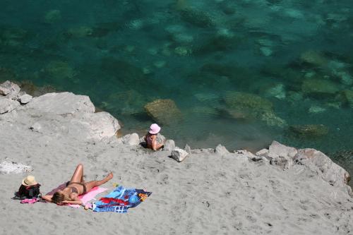 a woman laying on a beach next to the water at GRAB ethno village and camp in Šćepan-Polje