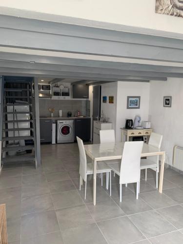 une salle à manger avec une table et des chaises blanches dans l'établissement L appart d Ange 2 idealement situe 47m2 entre le port et le village, à Gruissan