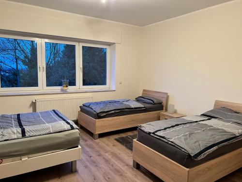a bedroom with two beds and two windows at Wiehengebirgs Fernblick App 4 in Bad Essen