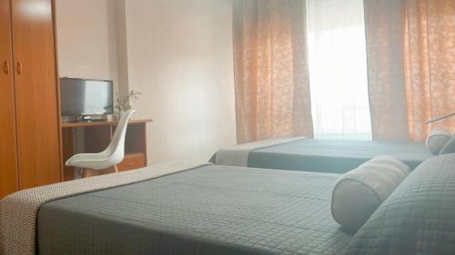 a bedroom with two beds and a chair and a television at Casa Pazos, Pedrafita do Cebreiro in Piedrafita