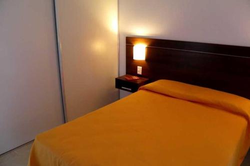 1 dormitorio con 1 cama con colcha de color naranja en Altos de Maipu Rosario en Rosario