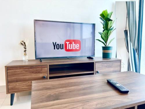 a flat screen tv sitting on top of a wooden entertainment center at L 1-5Pax Cozy 3Bed Setia Alam Trefoil Wifi SmartTV in Setia Alam