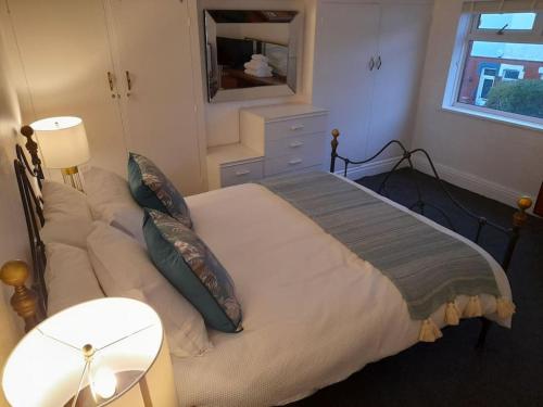 um quarto com uma cama grande com almofadas e um espelho em Fabulous terrace cottage em Blackpool