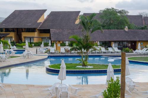 una piscina en un complejo con sombrillas y sillas en Flat Luxo em Gravatá Winterville, en Gravatá