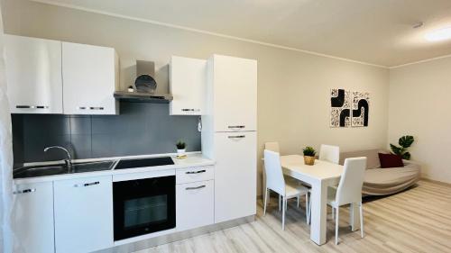 une cuisine avec des placards blancs et une table avec des chaises dans l'établissement Viareggio Deluxe, à Viareggio