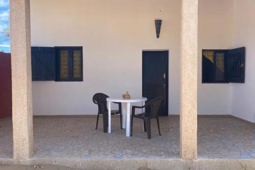 einen weißen Tisch und Stühle in einem weißen Zimmer in der Unterkunft Petite maison en bord de mer in Palmarin Nguèdj