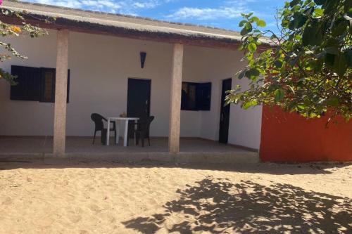 a white house with a table and chairs in it at Petite maison en bord de mer in Palmarin Nguèdj